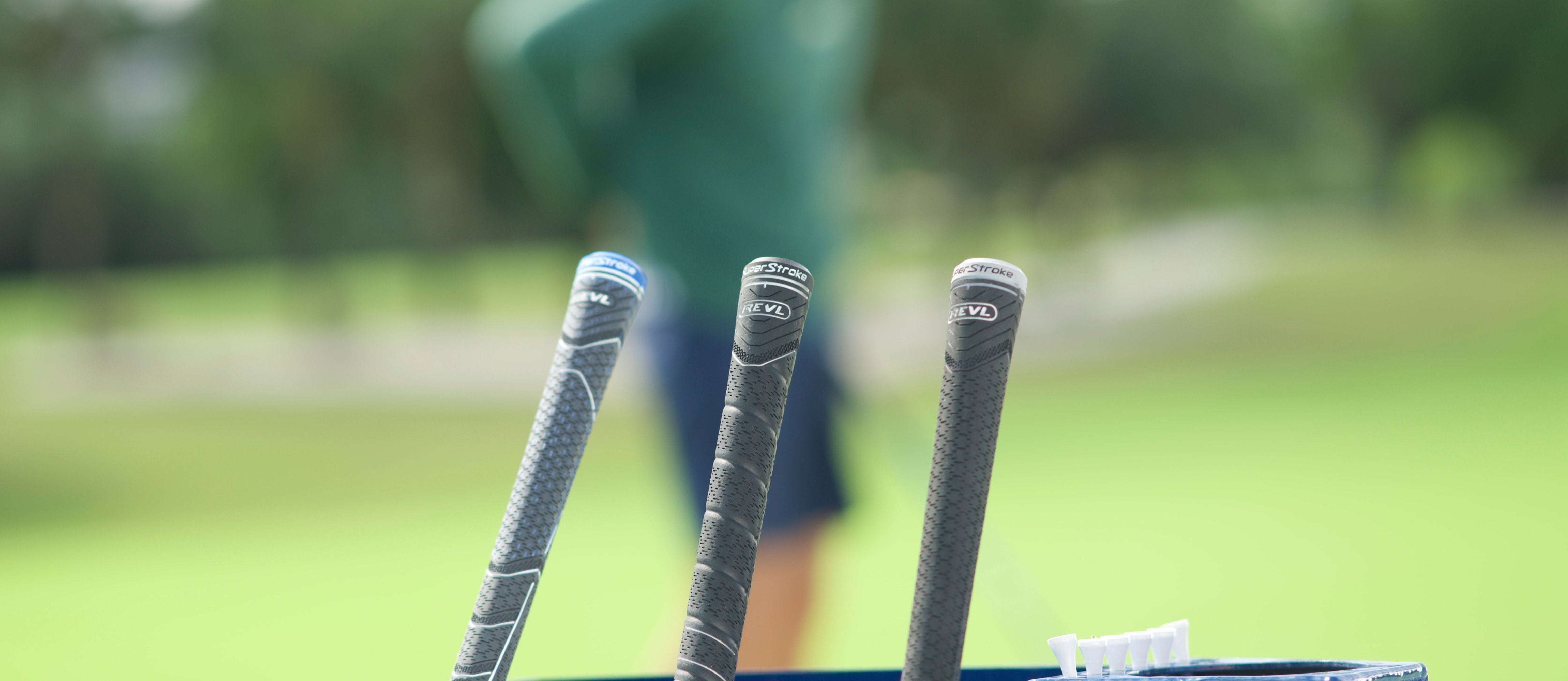 Two golf clubs with Traxion Tour SuperStroke club grips leaning on a golf bag